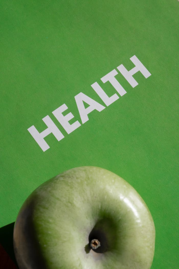 A green apple with Health text on a vibrant green background symbolizing wellness.
